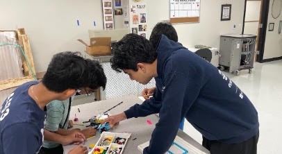 Two campers wiring up their robot's mechanisms