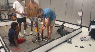 A counselor helping a team test their robot on the practice field